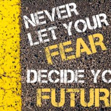 NEVER LET YOUR FEAR DECIDE YOUR FUTURE motivational quote.
Yellow paint line on the road against asphalt background. Concept image