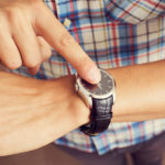 closeup of a young caucasian man tapping his forefinger on his wristwatch