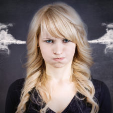 Closeup portrait angry young woman, blowing steam coming out of ears, about to have nervous atomic breakdown, isolated black background. Negative human emotions facial expression feelings attitude